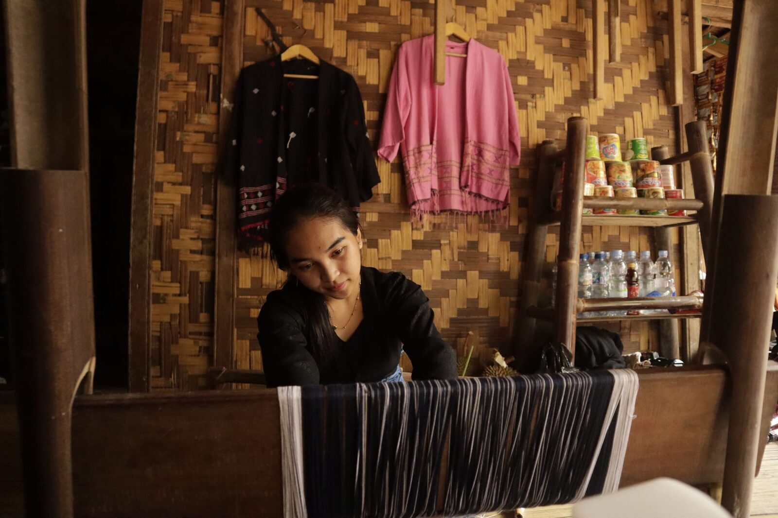 A weaver threading the loom in a village workshop — several around Sidemen let you watch and buy direct.