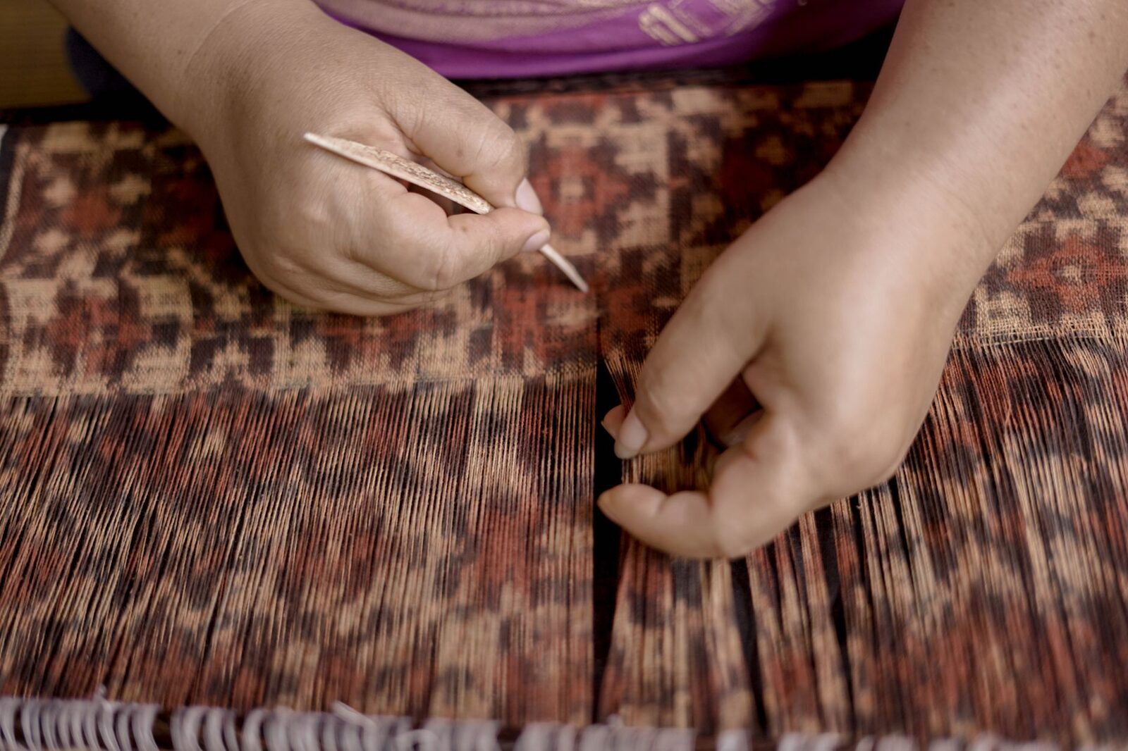 Hands at work on hand-woven cloth — Sidemen is one of Bali's centres for songket and endek weaving.