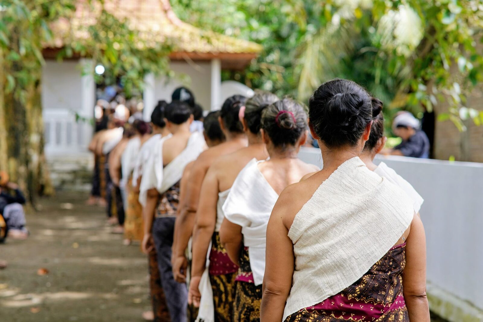 Temple dress in Bali — shoulders and knees covered, a sash at the waist. Away from the beach, dressing modestly earns respect first and quietly cuts unwanted attention second. Local worshippers pictured.