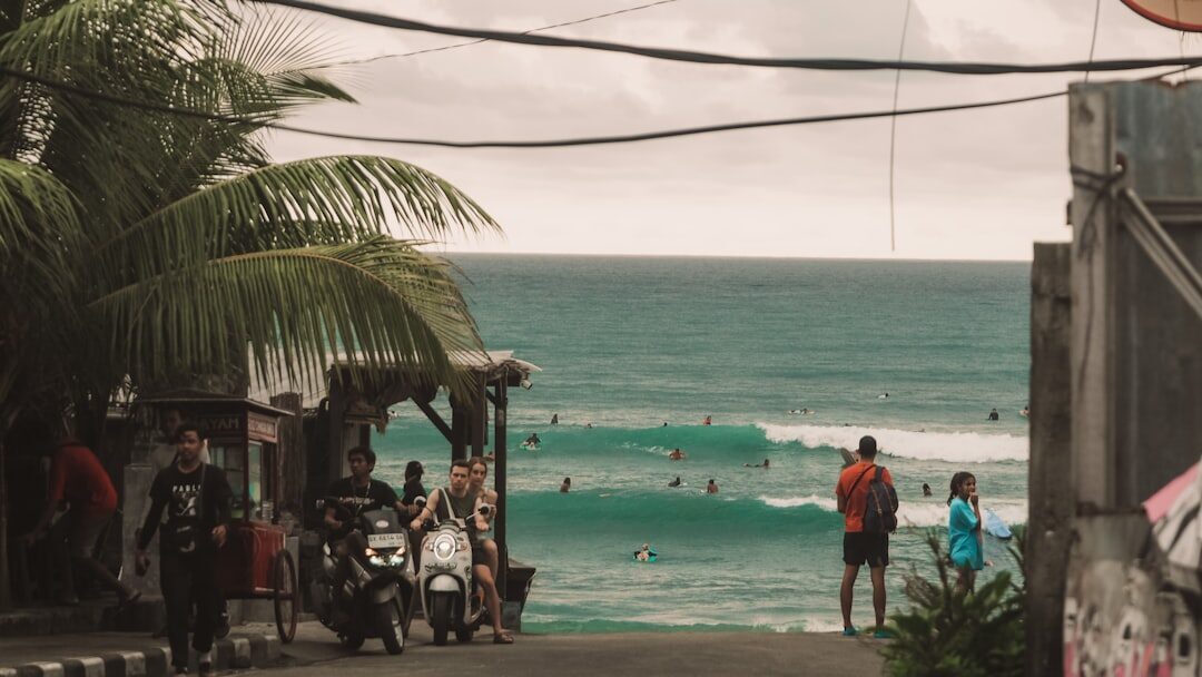 The beachfront strip behind a learn-to-surf break — warungs, boards and people in the shallows.