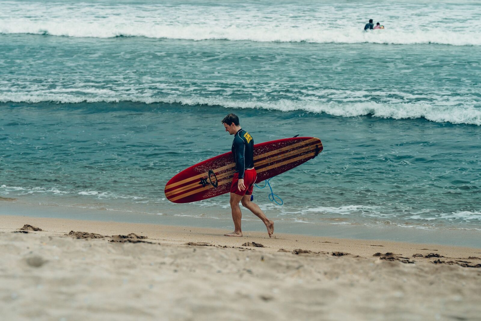 Carrying a board back up the sand after a session at a beginner beach break.