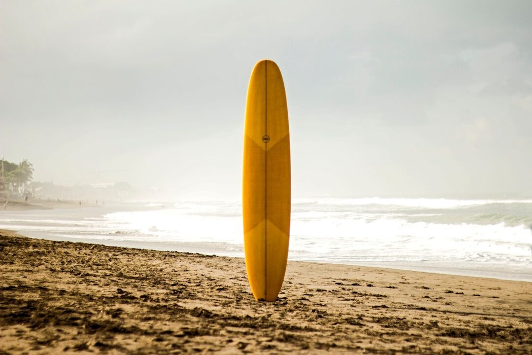 A longboard stood up on the sand at dawn — cheap board hire is everywhere in Bali.