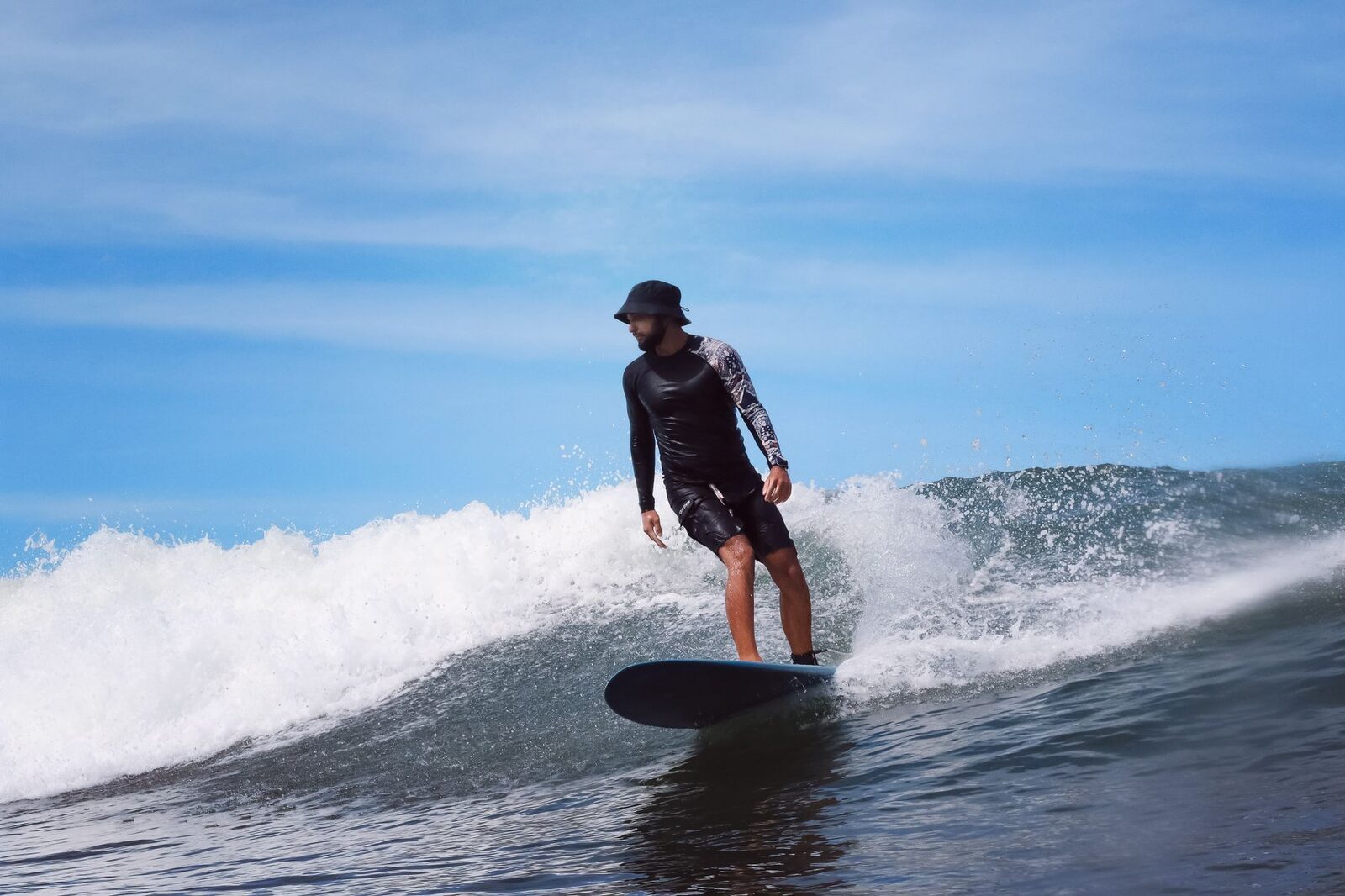 A surfer riding a long, forgiving shoulder — the kind of slow-peeling wave that makes a good intermediate step.