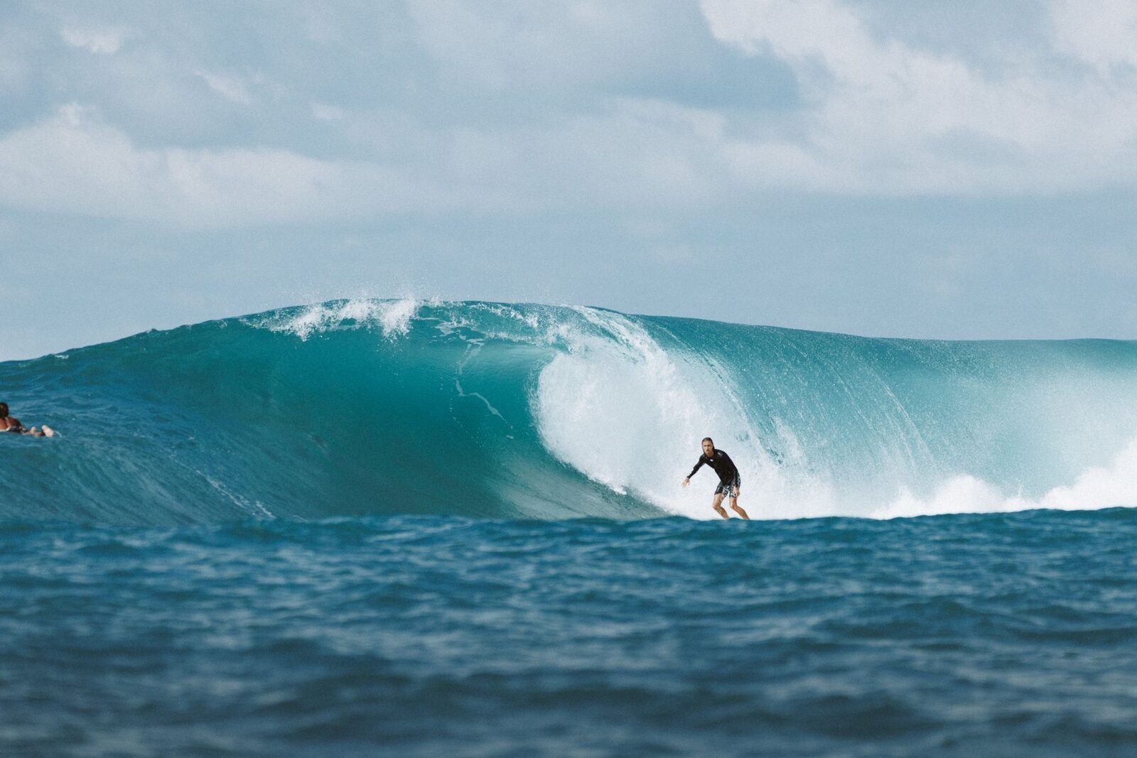 A surfer dropping into a big, clean Bukit reef wave on a working swell.