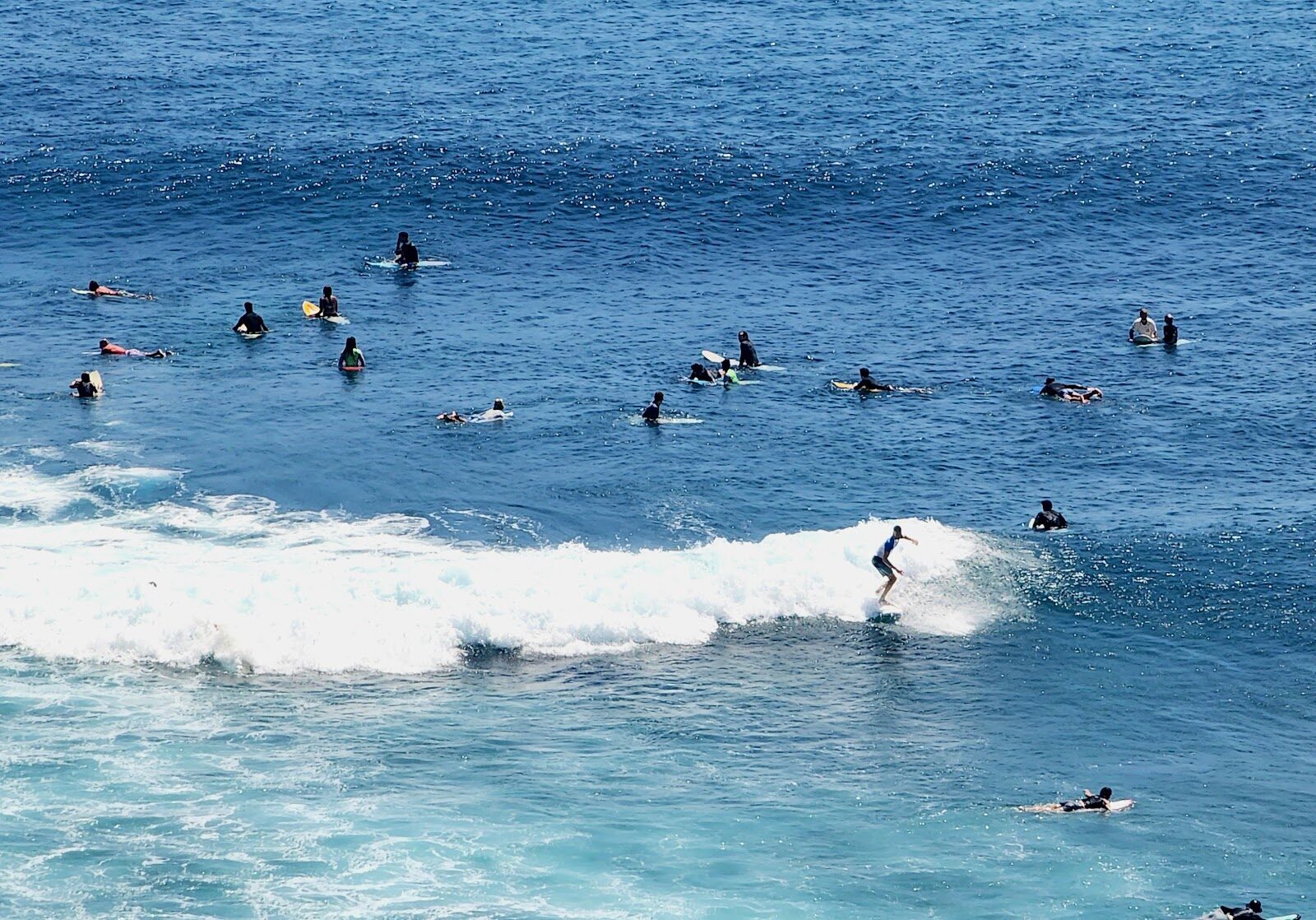 The lineup at a Bukit reef break, surfers waiting as a set rolls through.