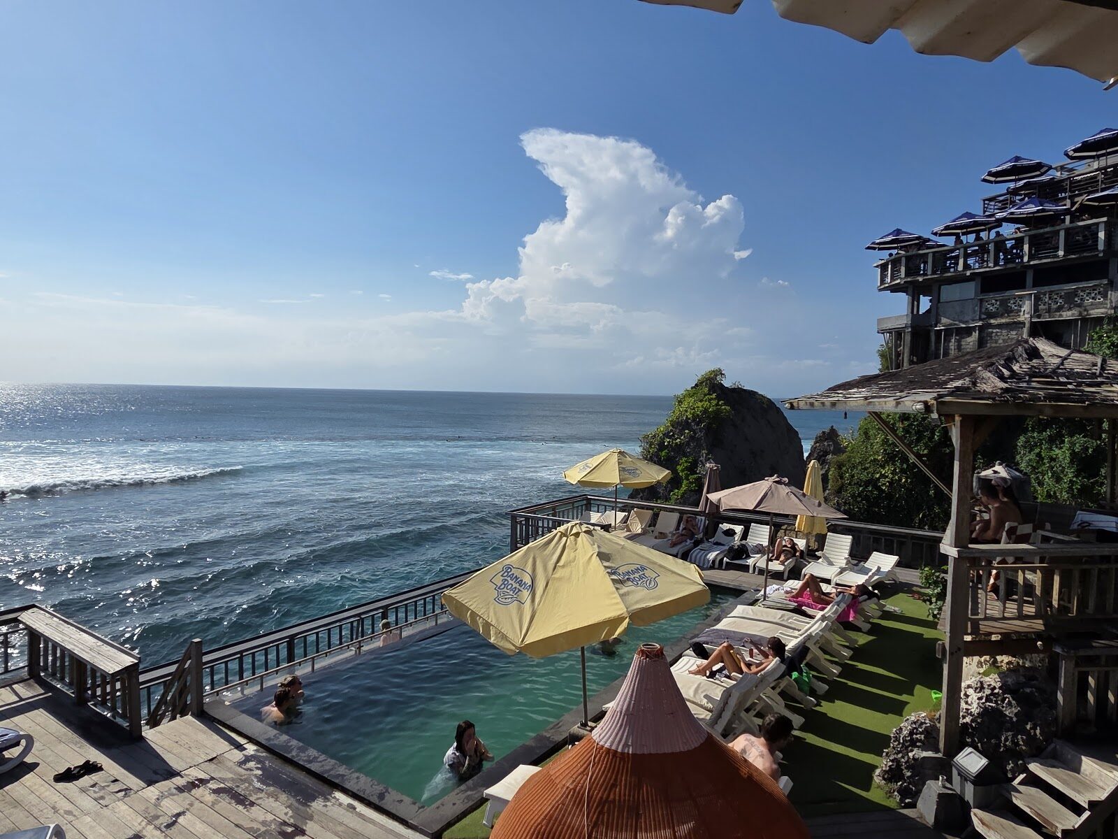 Looking down onto a Bukit reef break from a clifftop cafe — the view that tempts beginners onto waves they can't make.