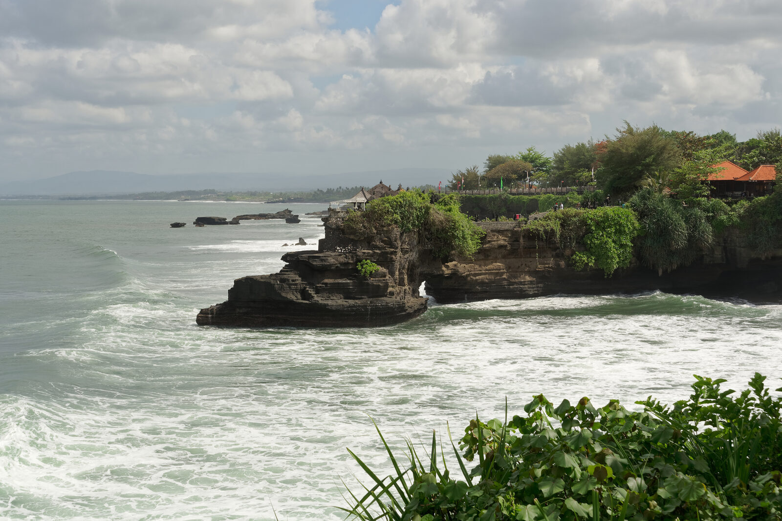 The Batu Bolong headland from the side, surf breaking below.