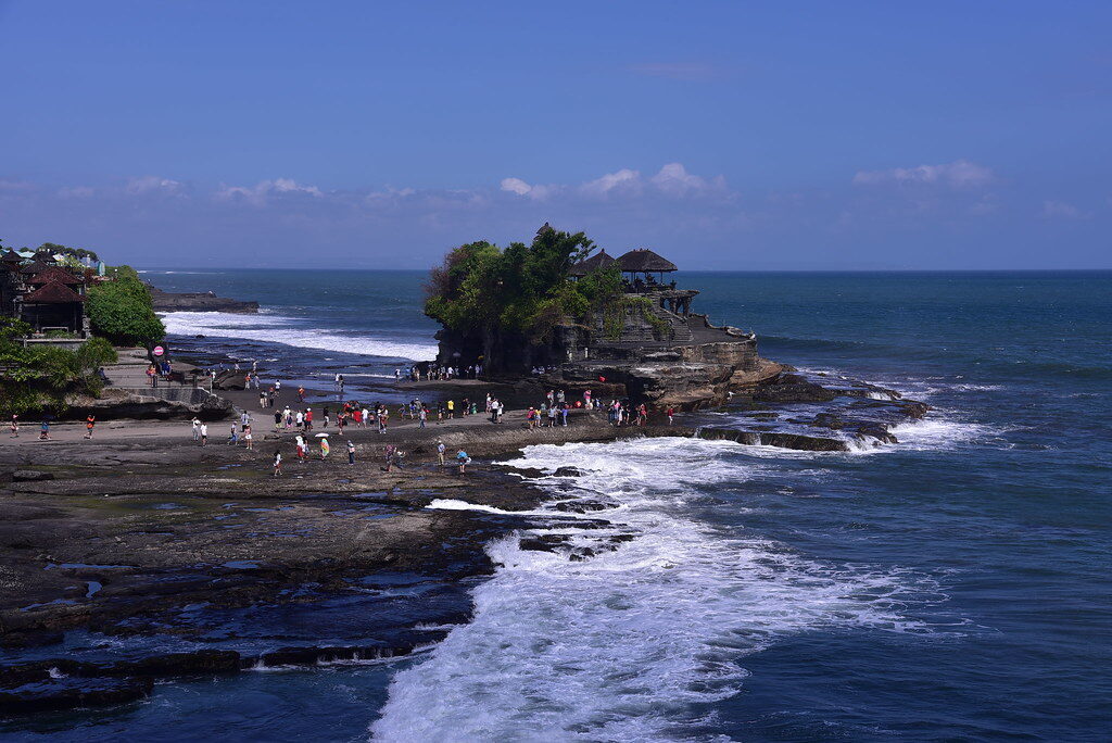 The tide out, people spread across the flats below the temple.