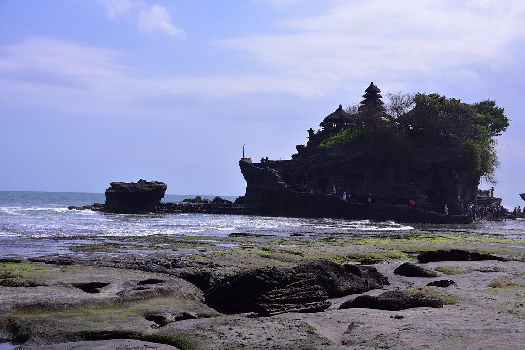 Wet rock and tide pools at the base — the walk you can only make at low tide.