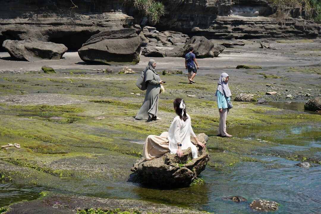 Visitors picking their way over the slick green rock at the base.