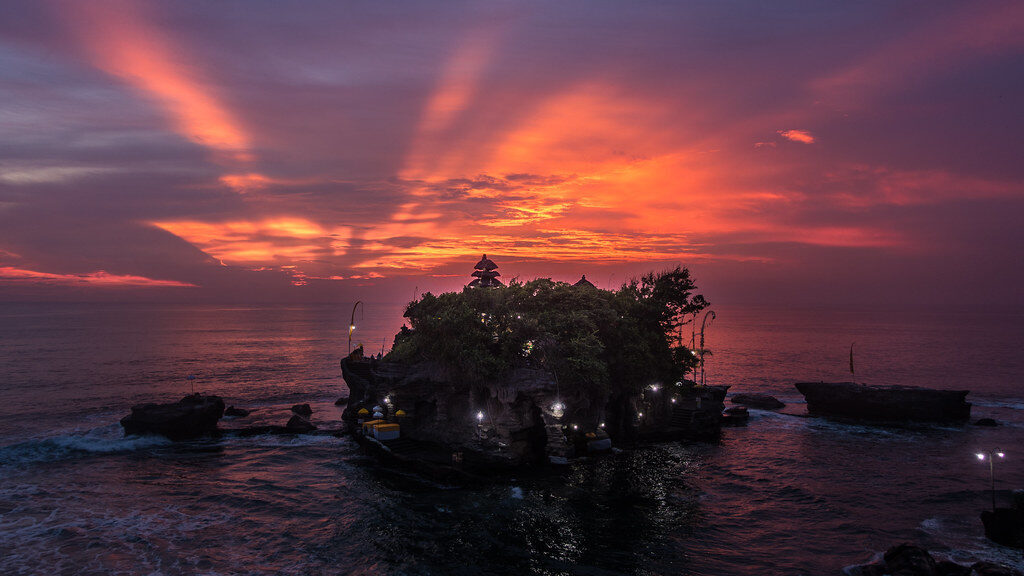 A fierce red sunburst behind the silhouetted temple.
