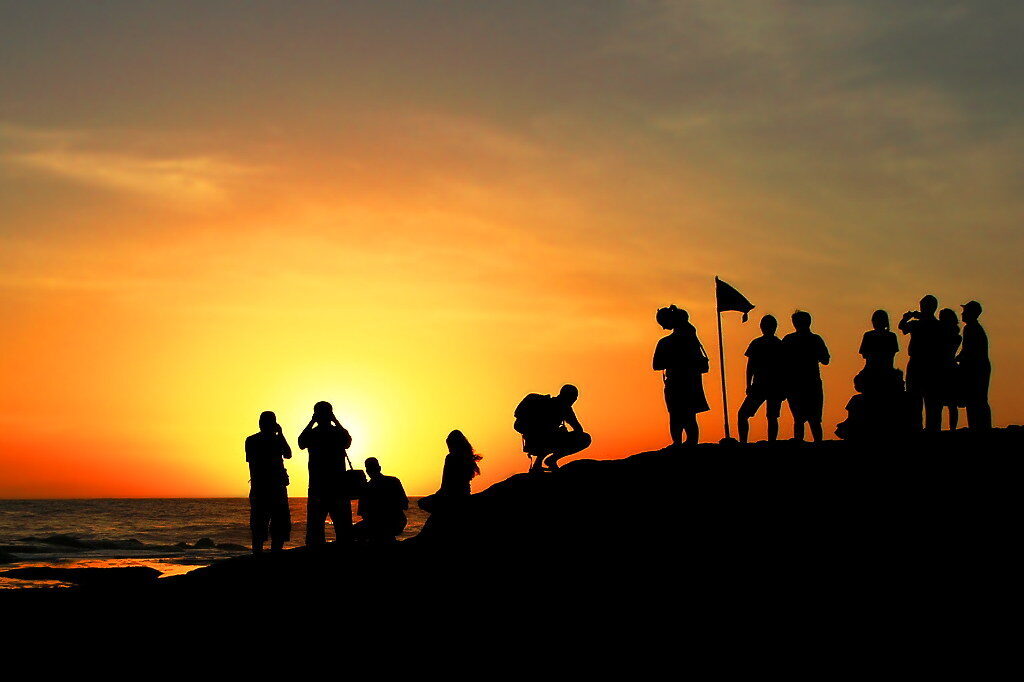Watchers reduced to silhouettes against the setting sun.
