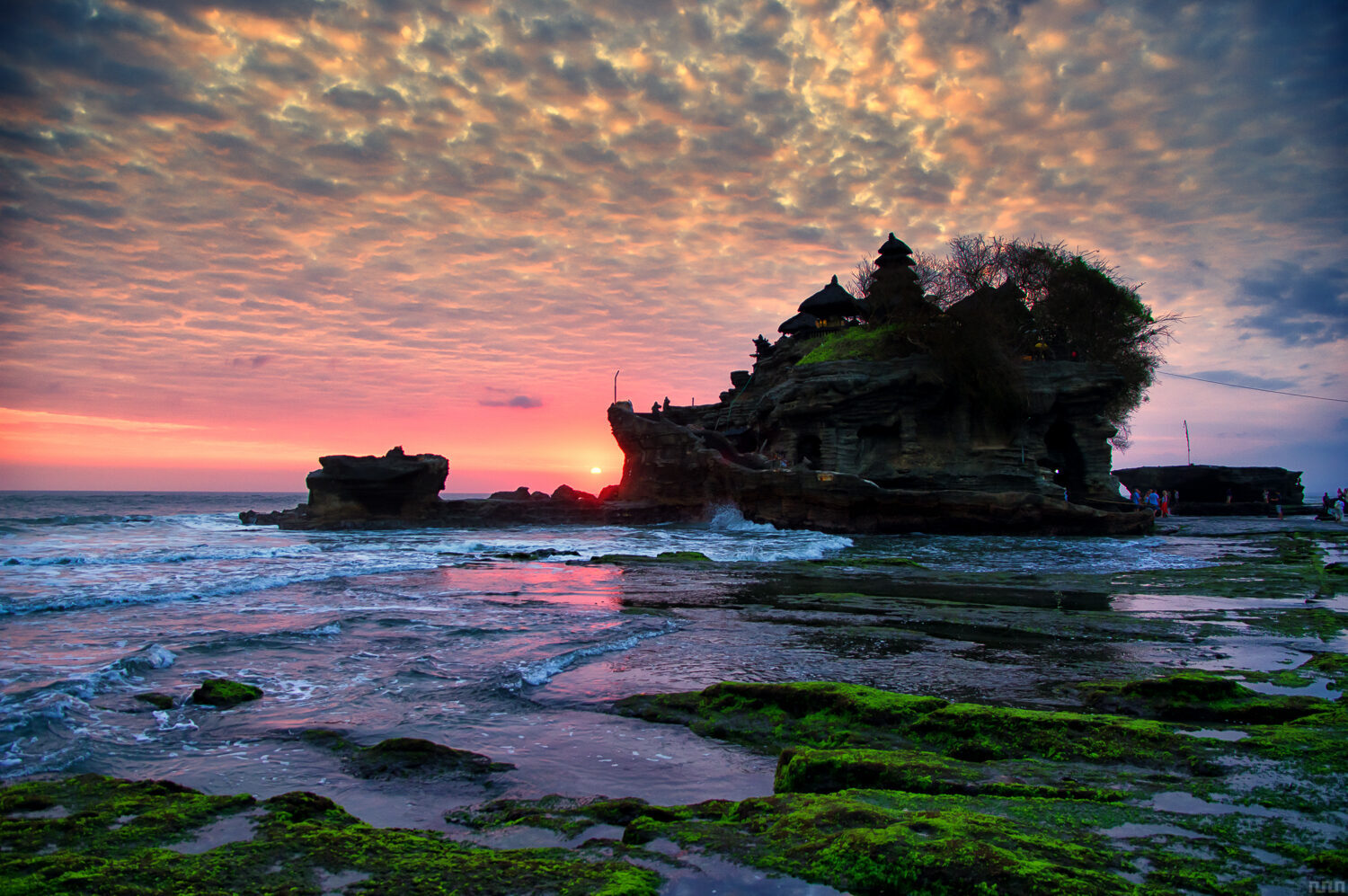 Pink afterglow over the rock shelf, the temple dark on its islet.