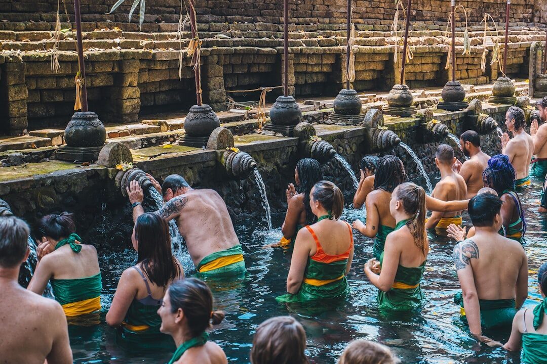 Bathers working along the line of spouts, heads bowed under the flow.