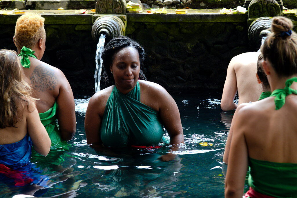 Visitors in wet sarongs taking their turn at the spouts.