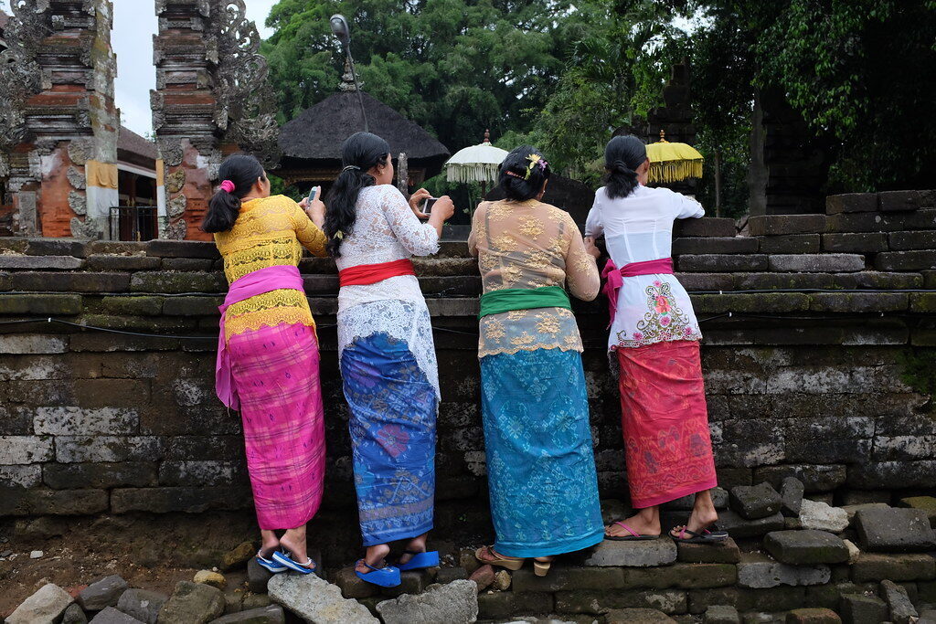 Balinese families in ceremonial dress praying at the shrine before entering the water.