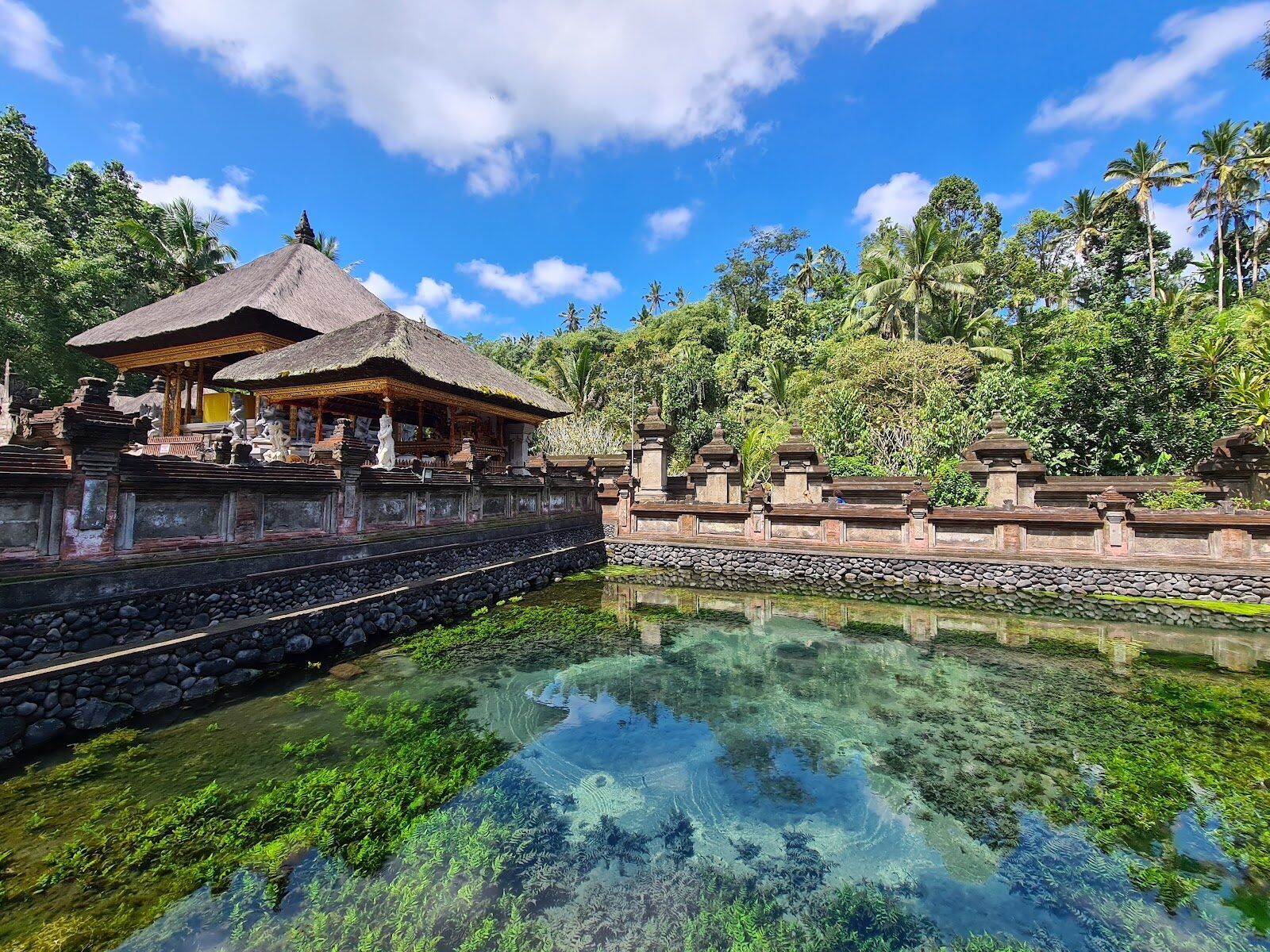 The clear spring pond inside the sanctum, the tiered meru shrines rising behind it.