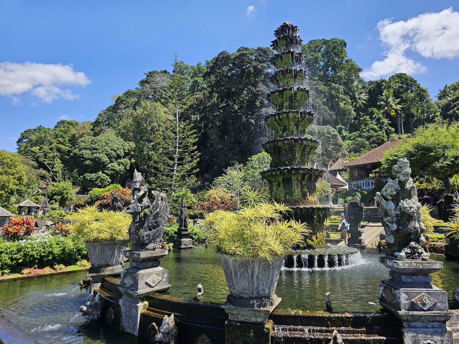 The tiered fountain and its surrounding statues on a bright day.