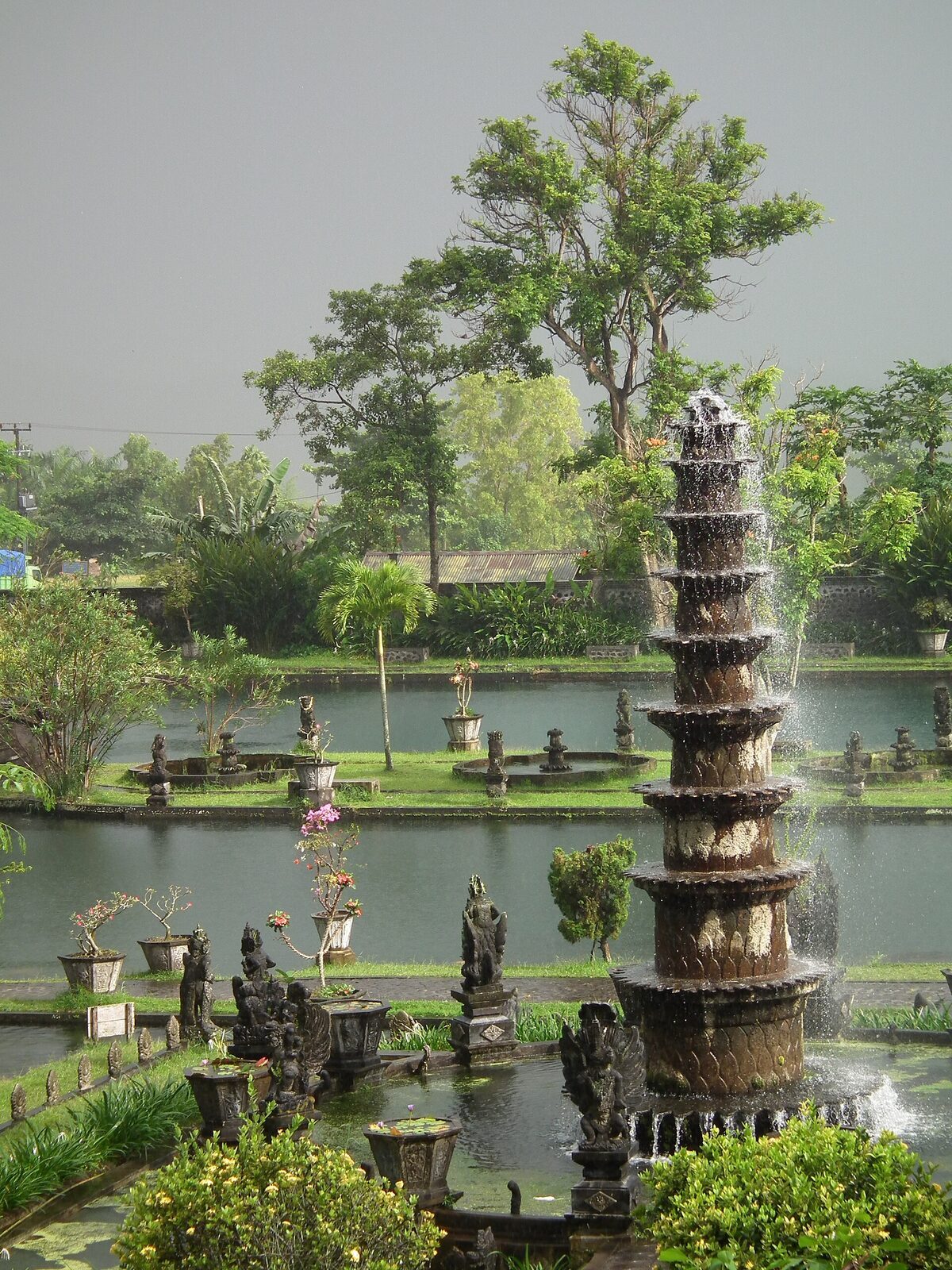 The tiered Nawa Sanga fountain and the koi ponds of the lower garden, statues dotted across the water — Tirta Gangga's whole compact layout in one frame.