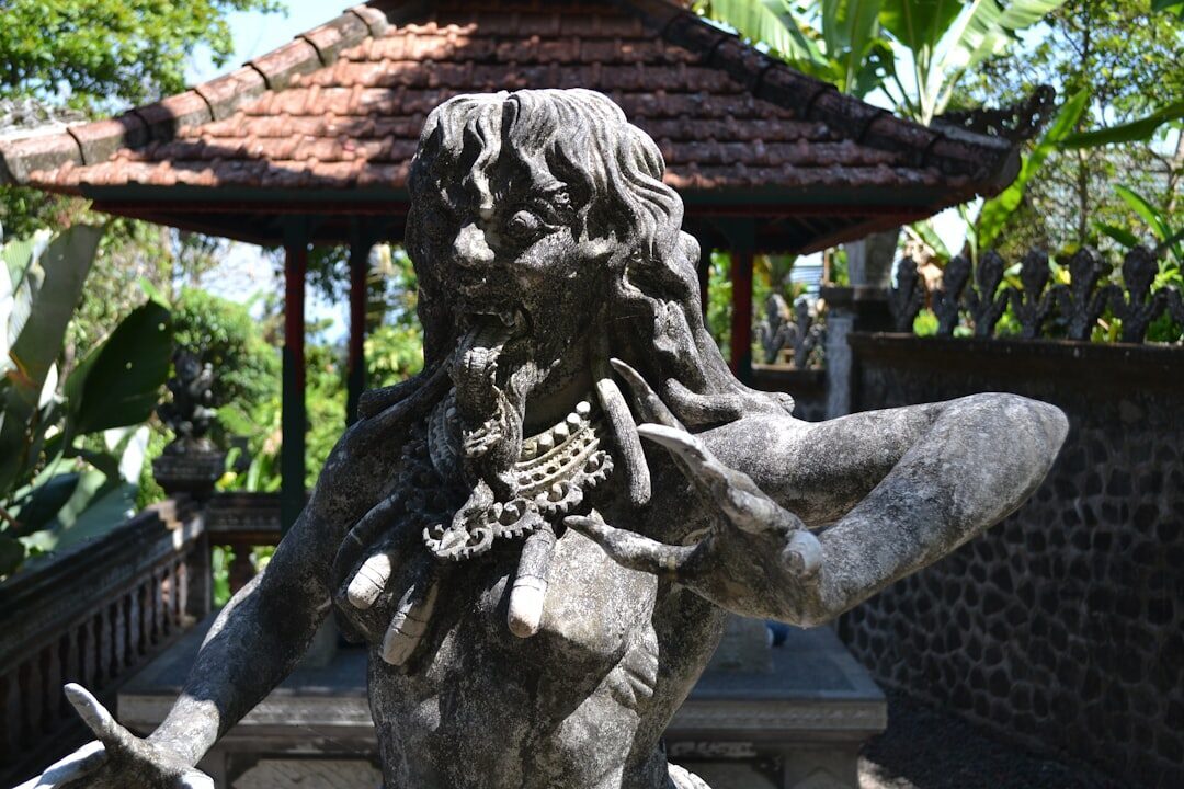 A carved stone figure sheltering under a garden pavilion.