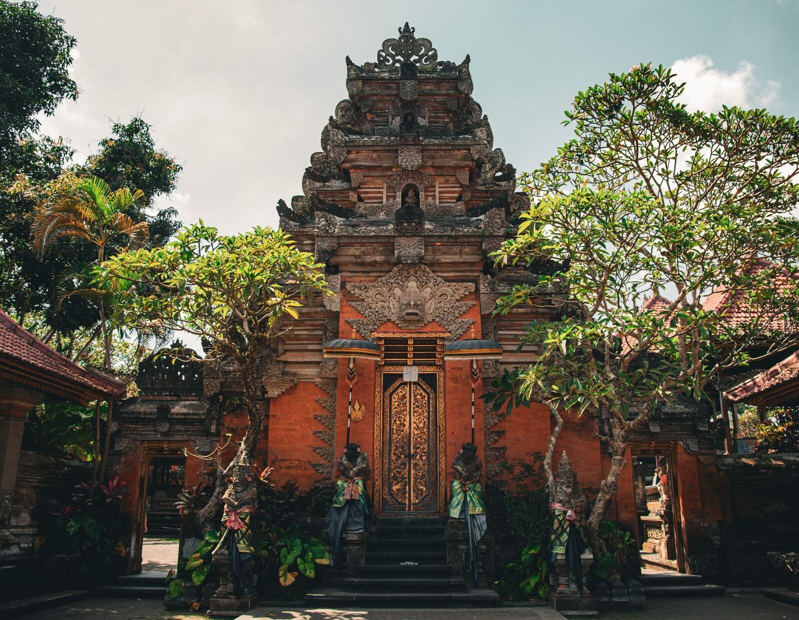 An ornate carved-and-gilded palace doorway, flanked by guardian statues.
