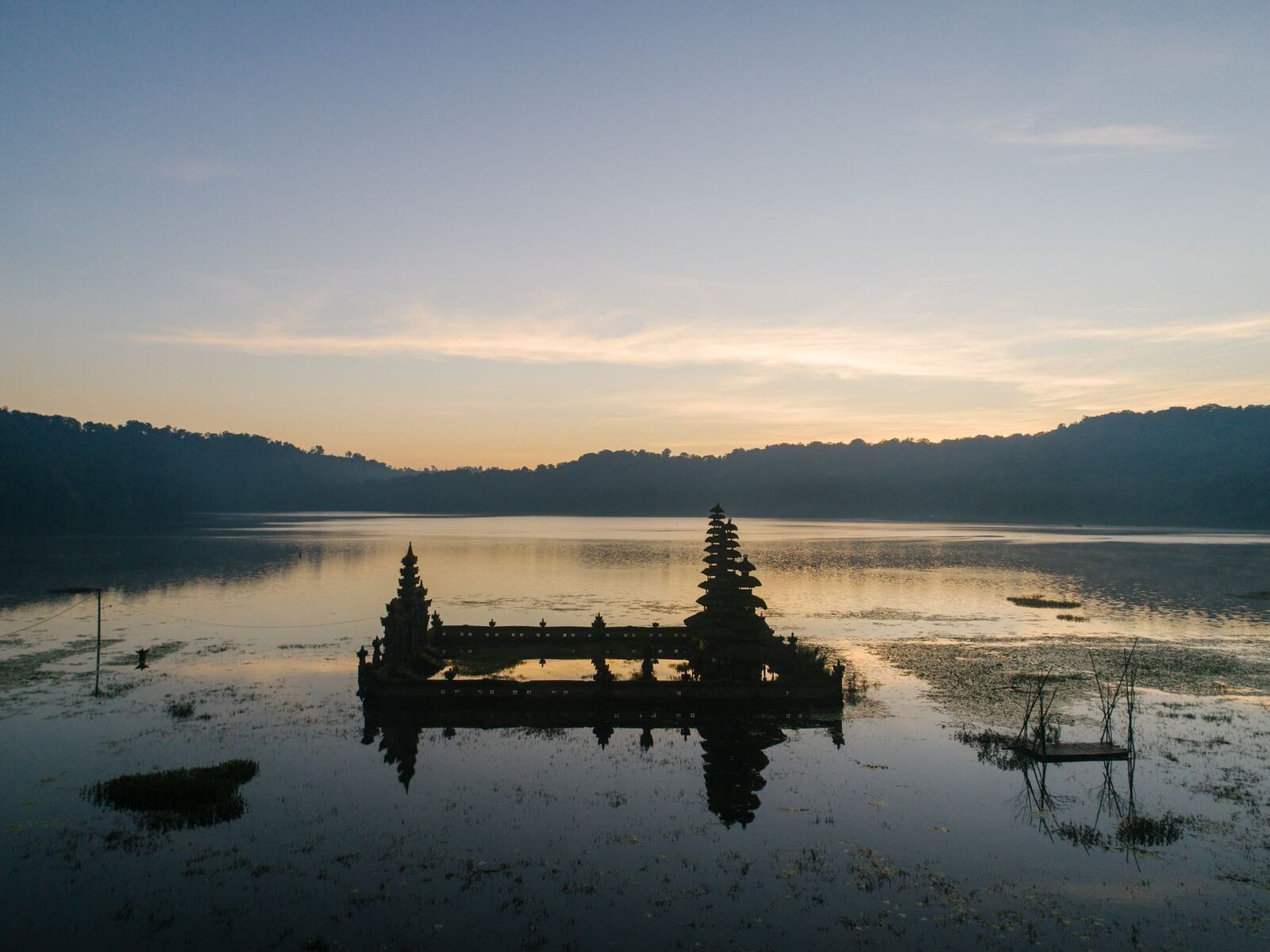 Dawn over one of the highland lakes, a small lake shrine silhouetted on the water.