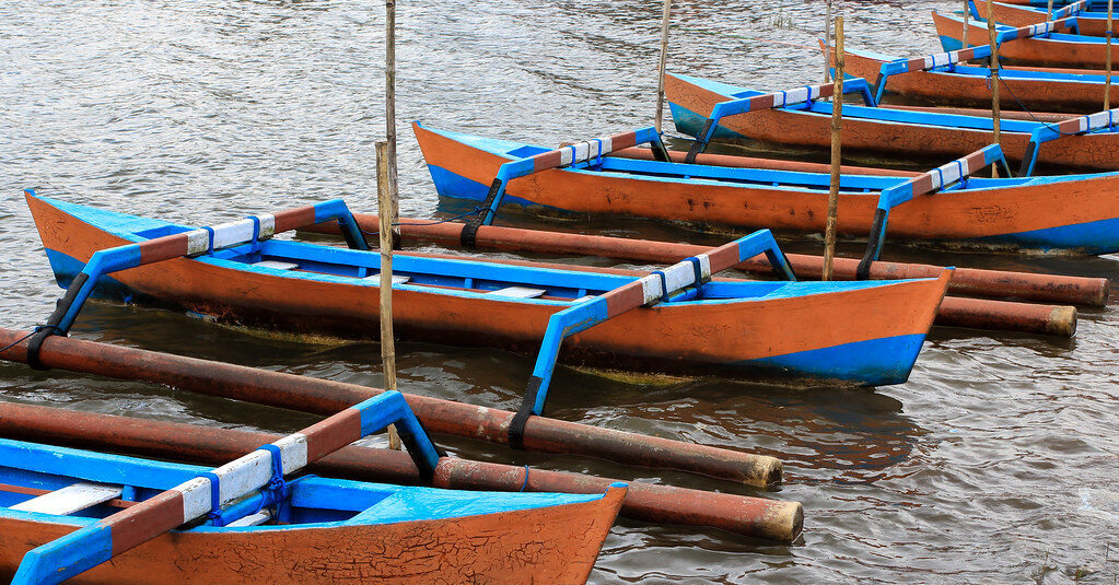 A line of outrigger jukung moored on the lake.