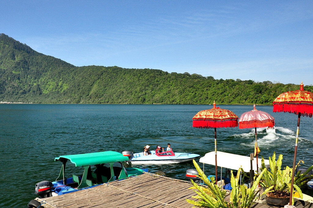 Dragon boats with red umbrellas waiting on the water — lake rides run alongside the temple.