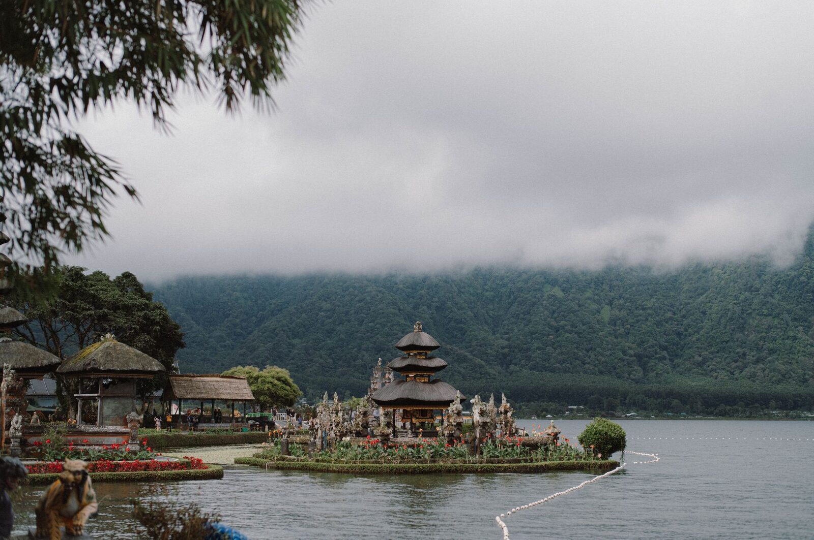The floating shrines seen across the lake, jukung boats drawn up at the shore.