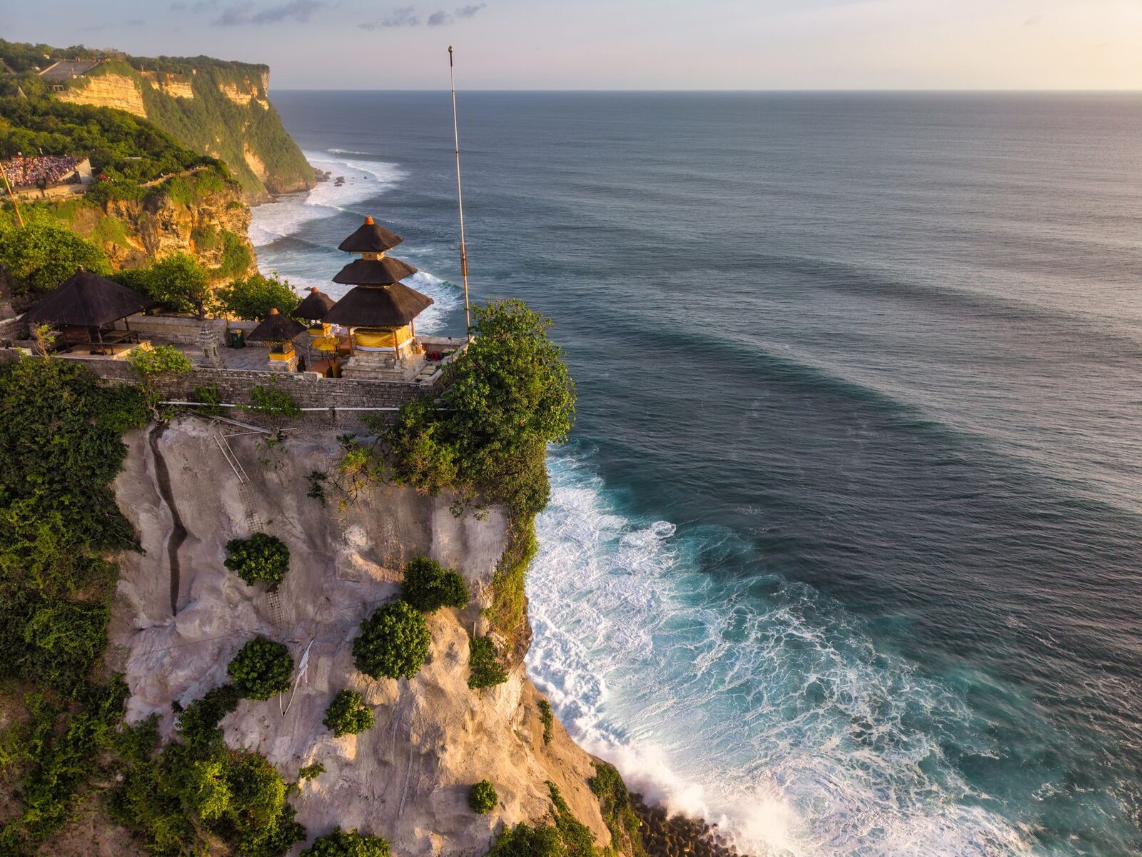 The temple's shrines on the cliff edge, the surf breaking white at the foot of the rock.