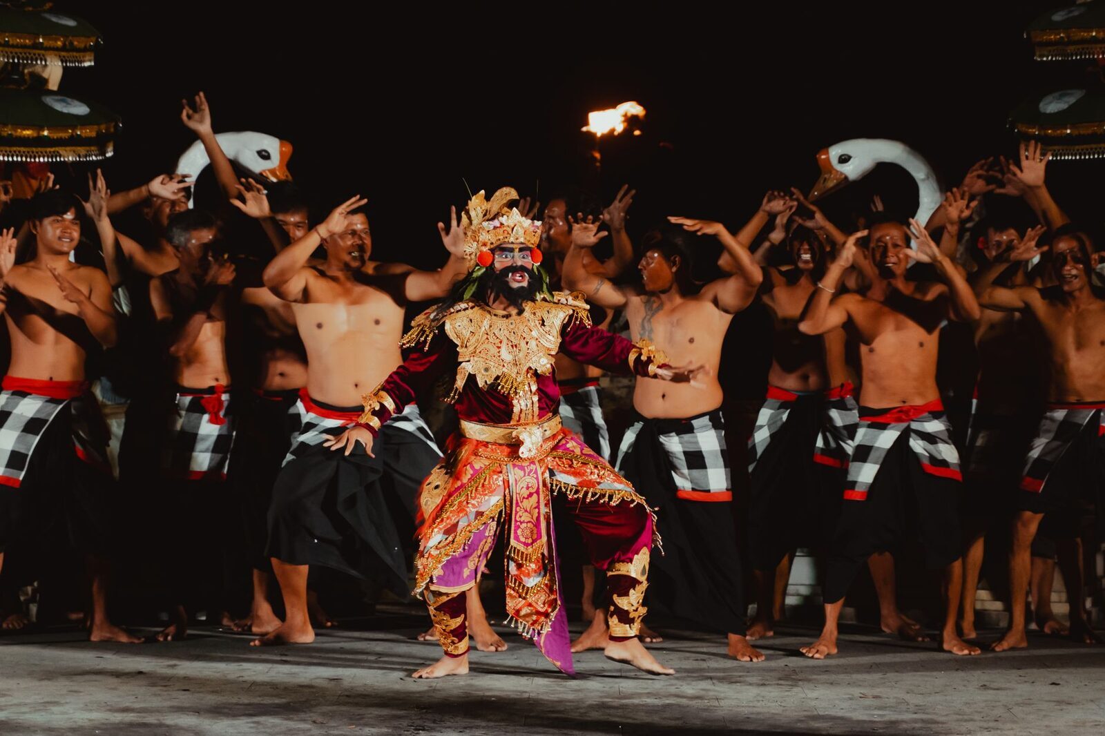 A costumed lead at the centre of the ring, the chanting men banked behind.
