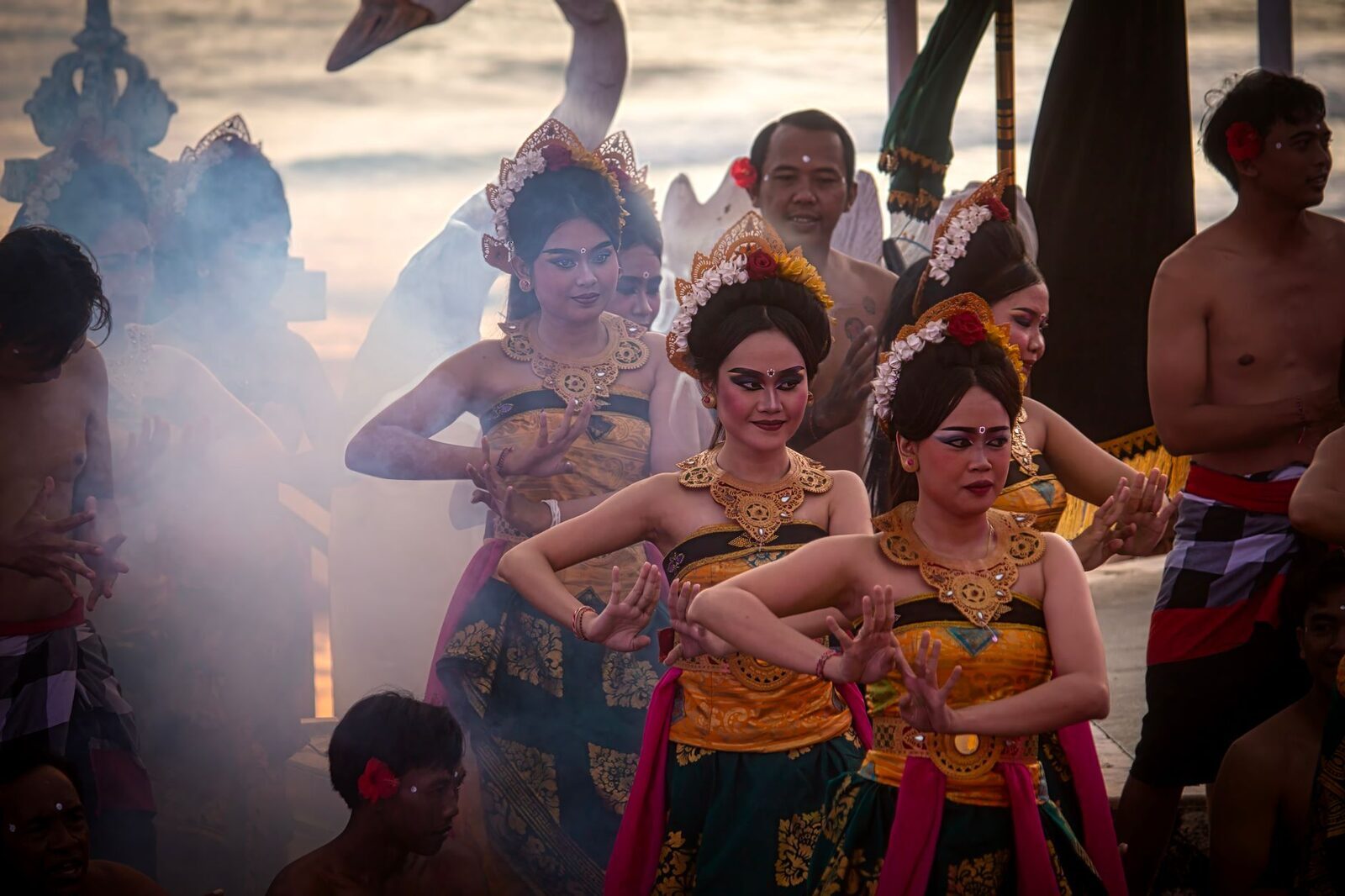 Female dancers in gilded brocade as Sita, lit through torch-smoke.