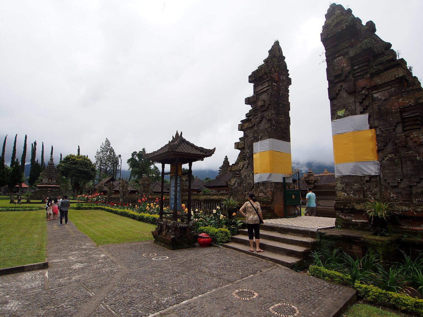 A Balinese split gate opening onto the temple grounds, a mountain beyond — the threshold you pass before the courtyards.