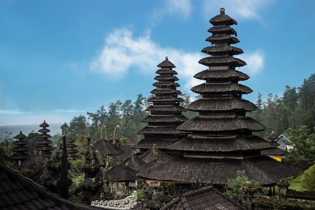 A tiered black-thatched meru against the sky — the odd number of roofs encodes the rank of the deity it honours. (This tall example is the postcard kind; Uluwatu's own meru are modest three-tier shrines.)