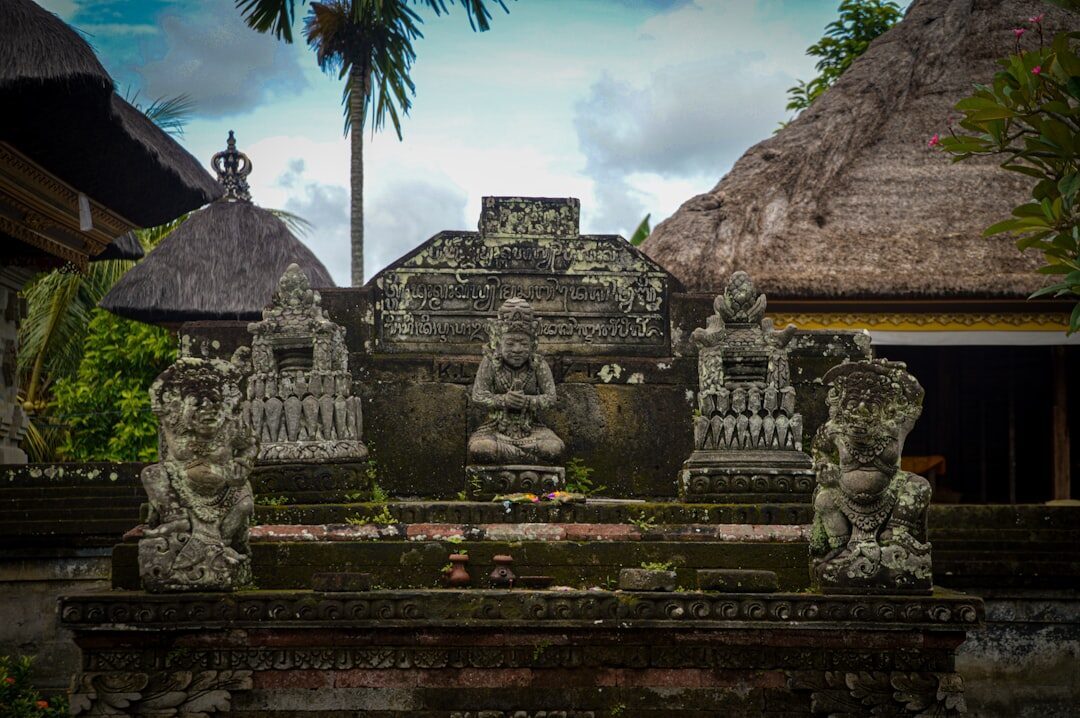 Stone altars and shrines within a Balinese temple, flanked by guardians.