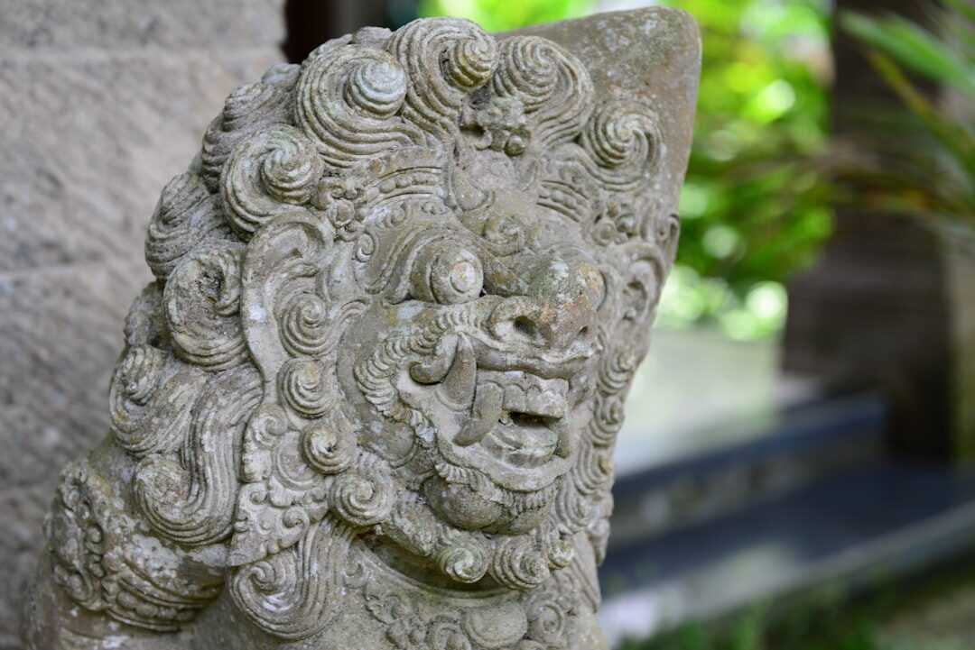 A moss-softened guardian relief cut from grey temple stone.