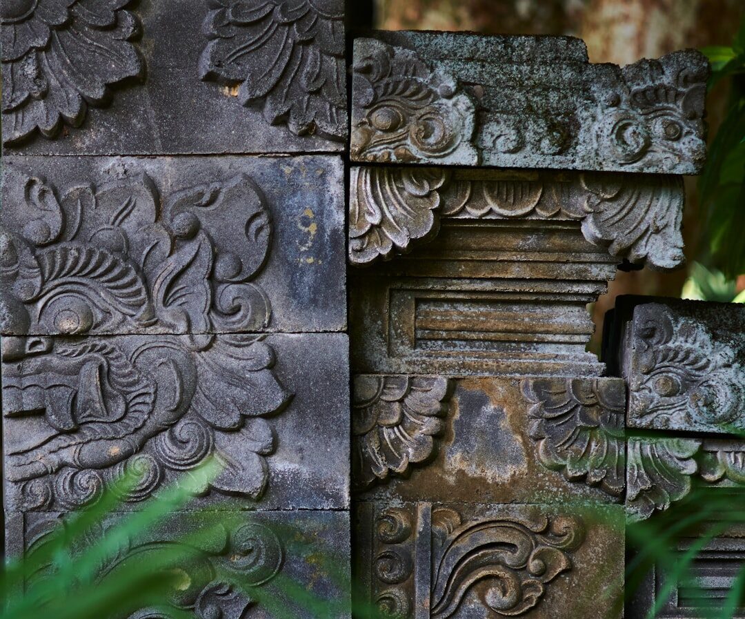 Carved stone panels and interlocking relief patterns on a Balinese temple wall.