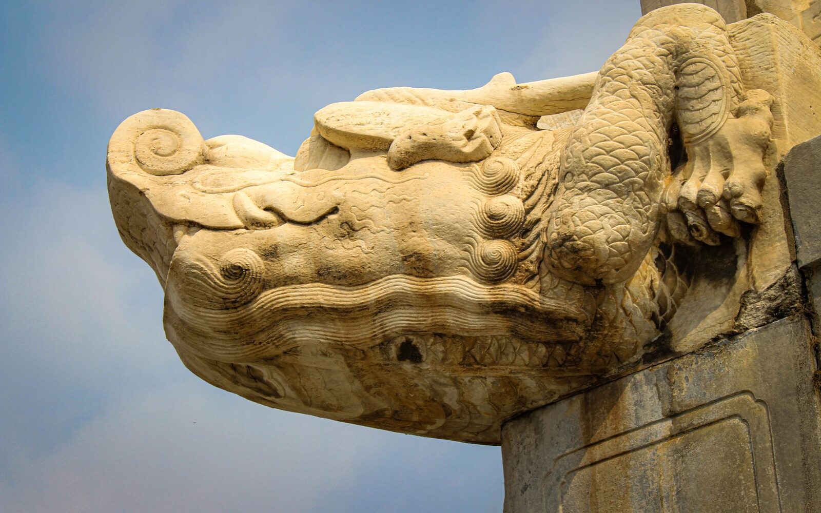 A carved makara-style stone waterspout against the sky.