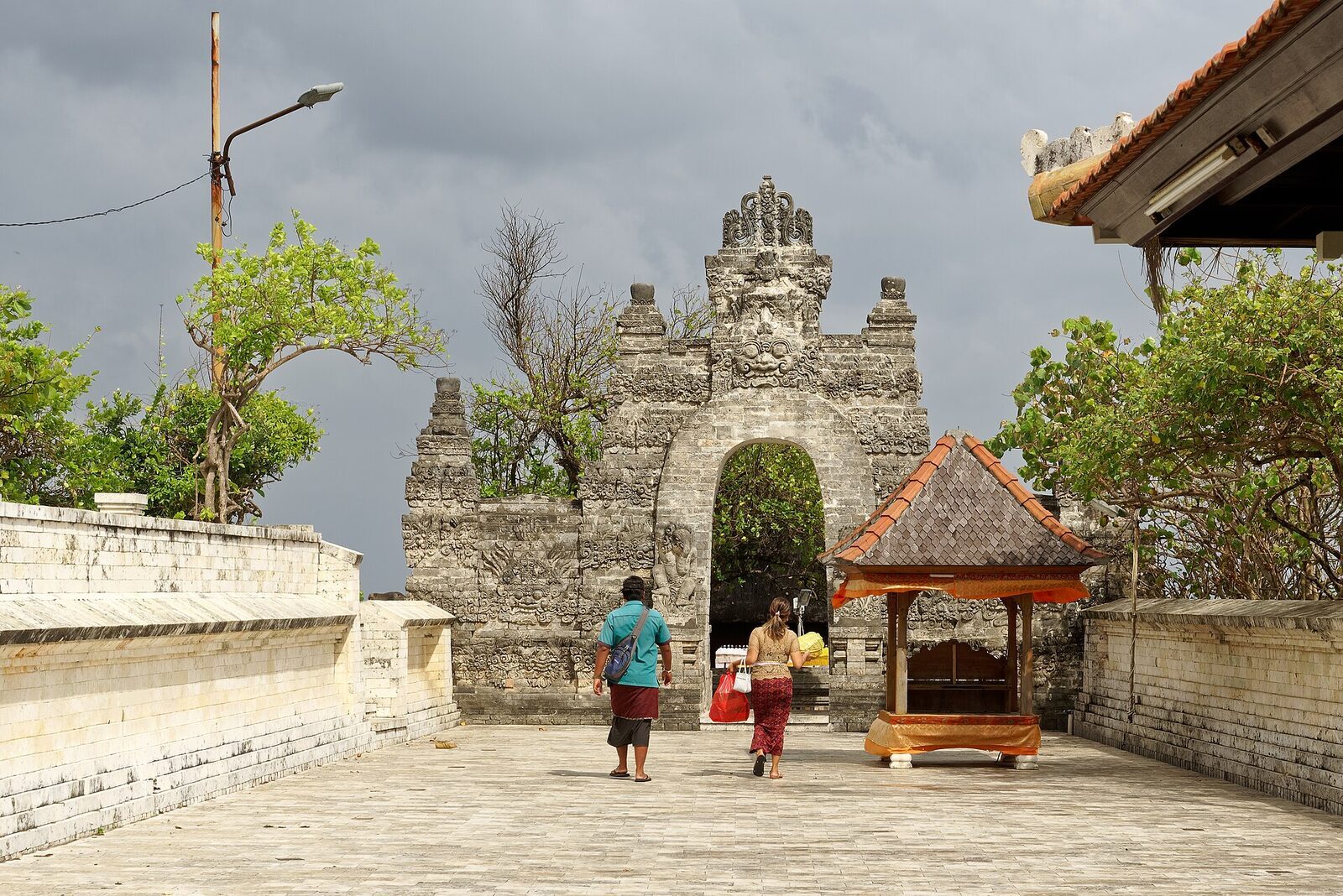 Worshippers carrying offerings through a carved stone gateway at Uluwatu temple