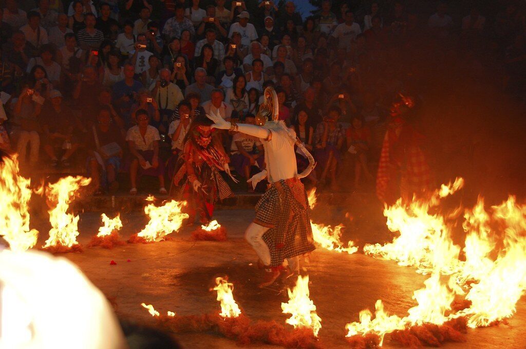 The fire-kicking climax — a performer scattering a bonfire of coconut husks.