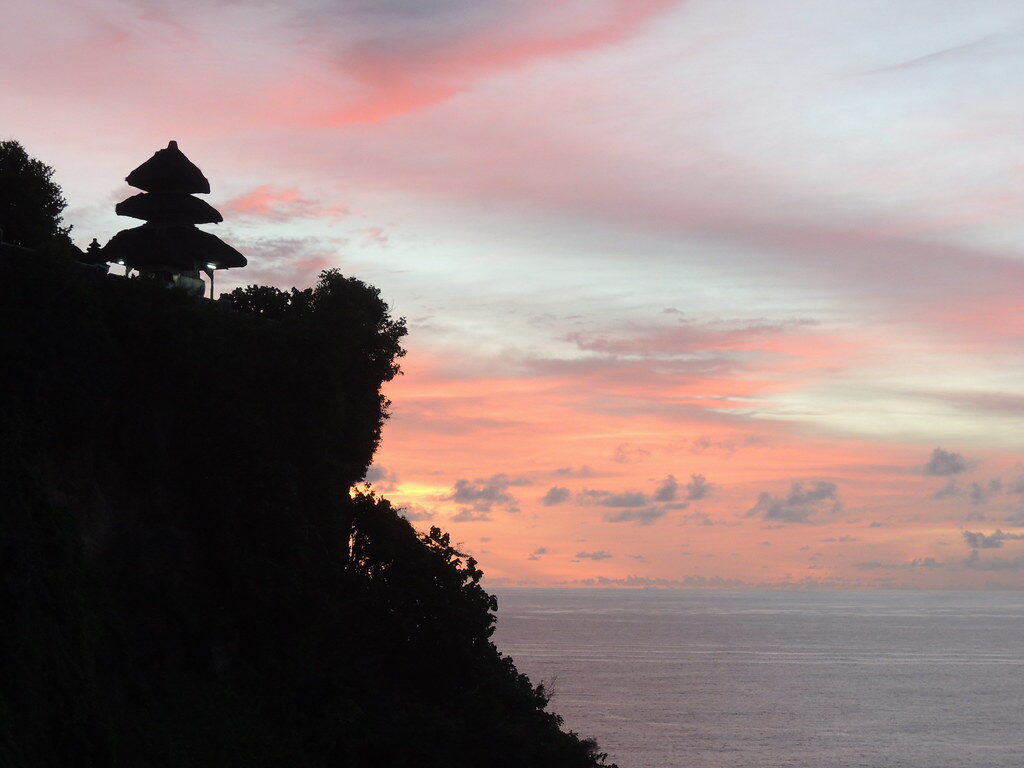 Pink dusk sky behind a clifftop pagoda at Uluwatu.