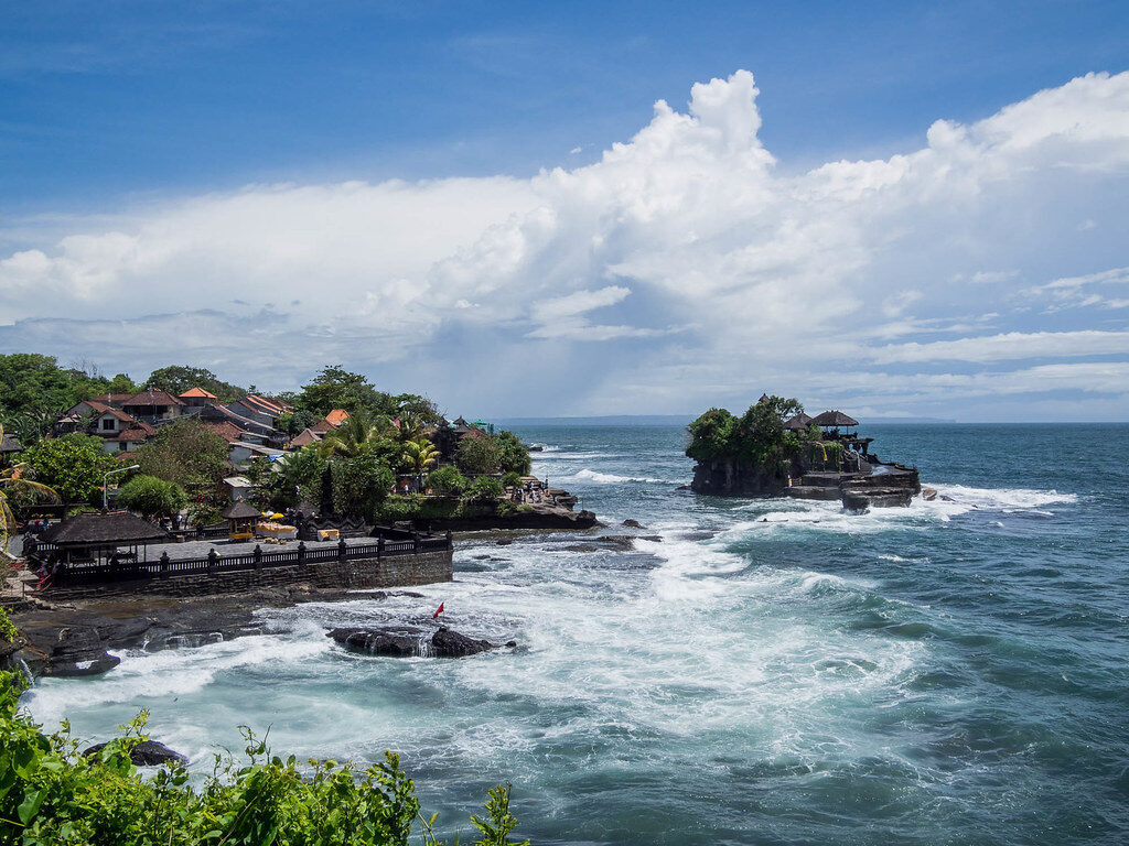 The wider Tanah Lot headland — shrines, sea and the village behind.