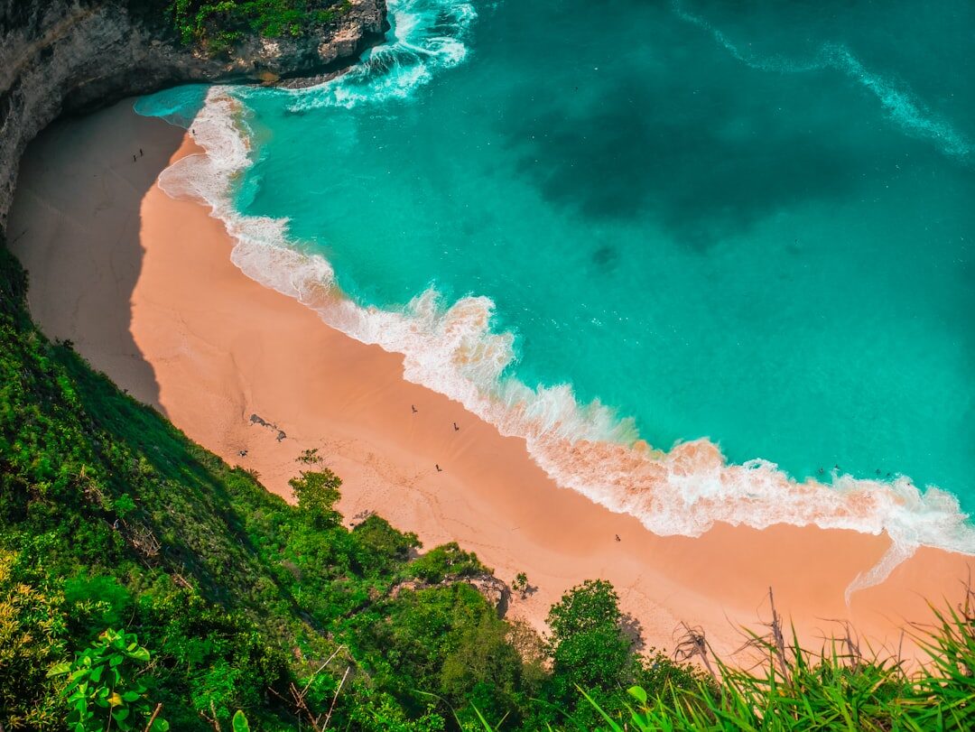 A turquoise Bali cove below the cliffs — the wet, sun-drenched coast you pack a dry bag, reef-safe sunscreen and reef shoes for.