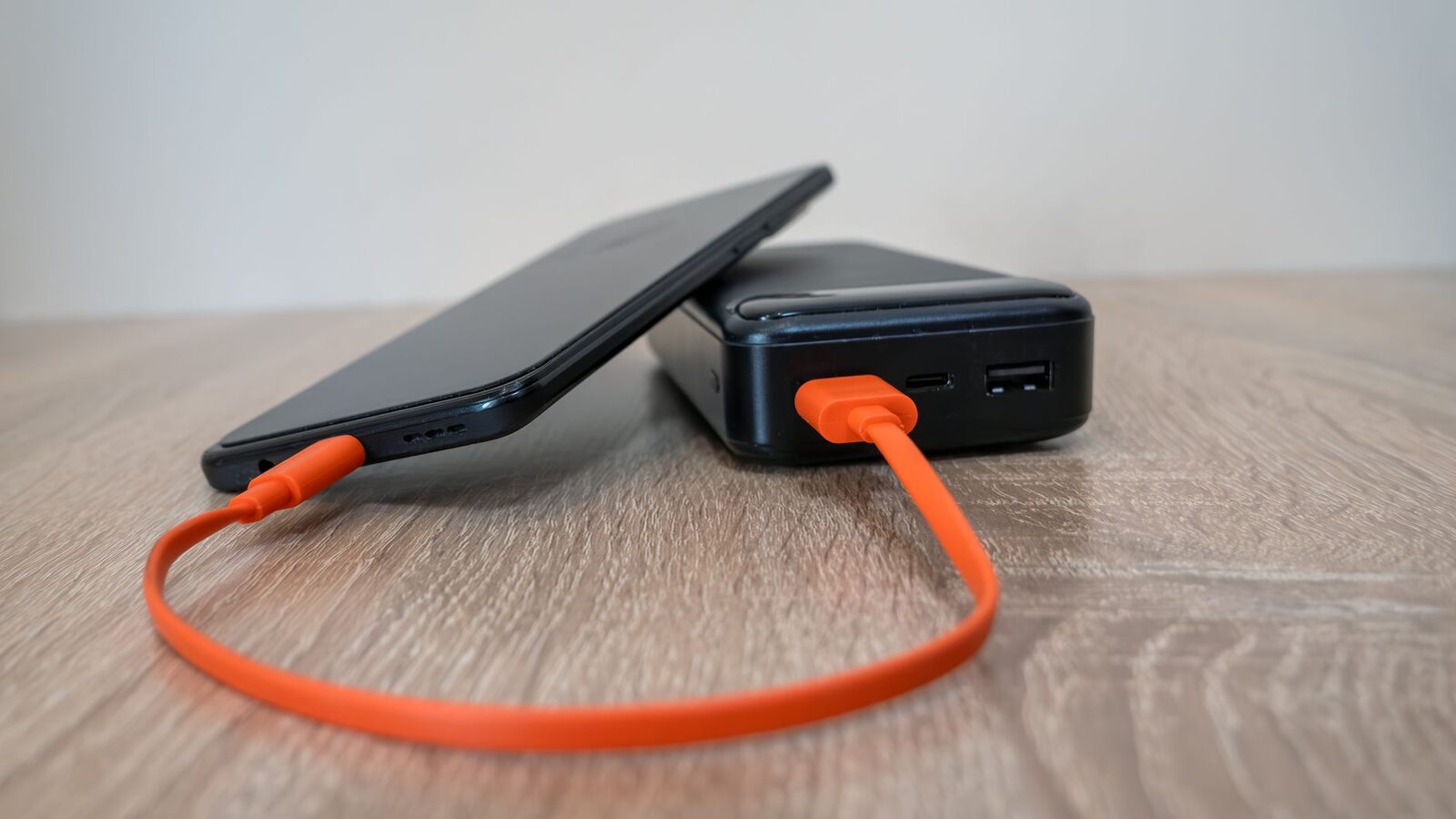 A power bank topping up a phone on a table — one of the most-used things in the bag on a long day out.
