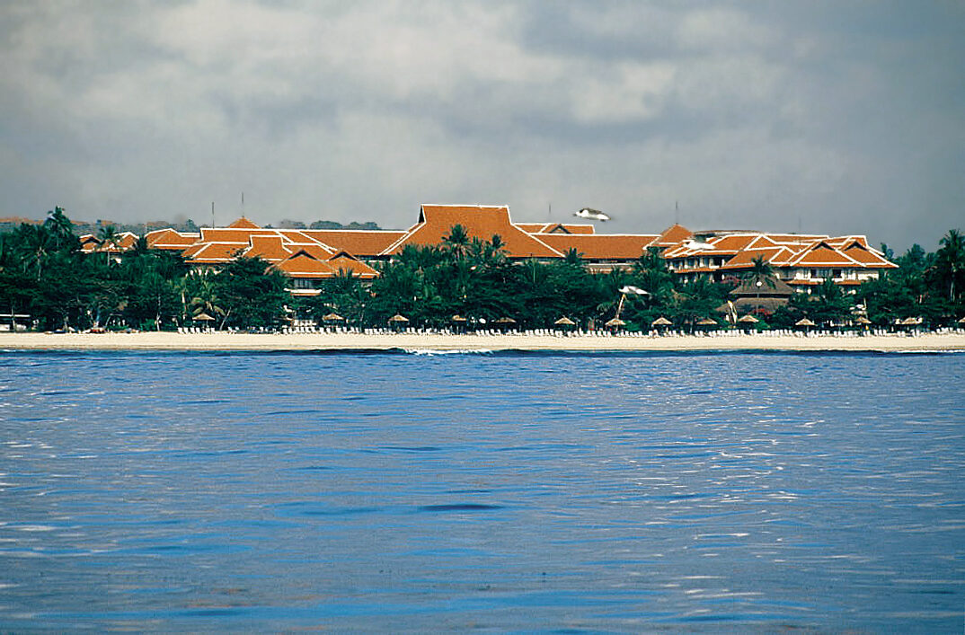 Big resorts lining a calm Nusa Dua bay across flat water.