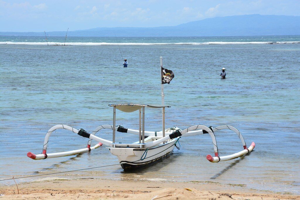 Brightly painted jukung fishing boats pulled up on the calm shallows.