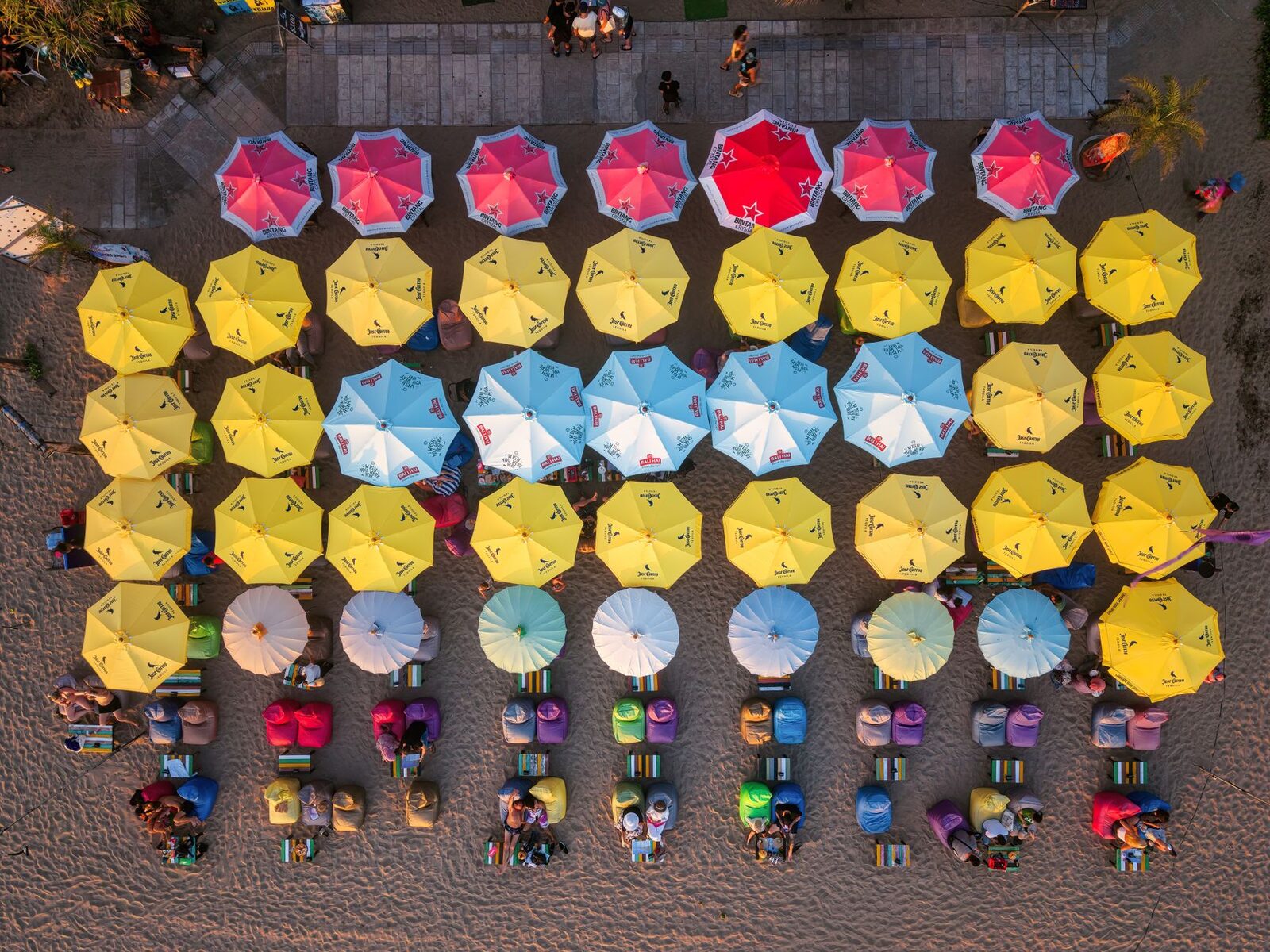 Beach-club umbrellas from above — the colour and order of the Seminyak strip.