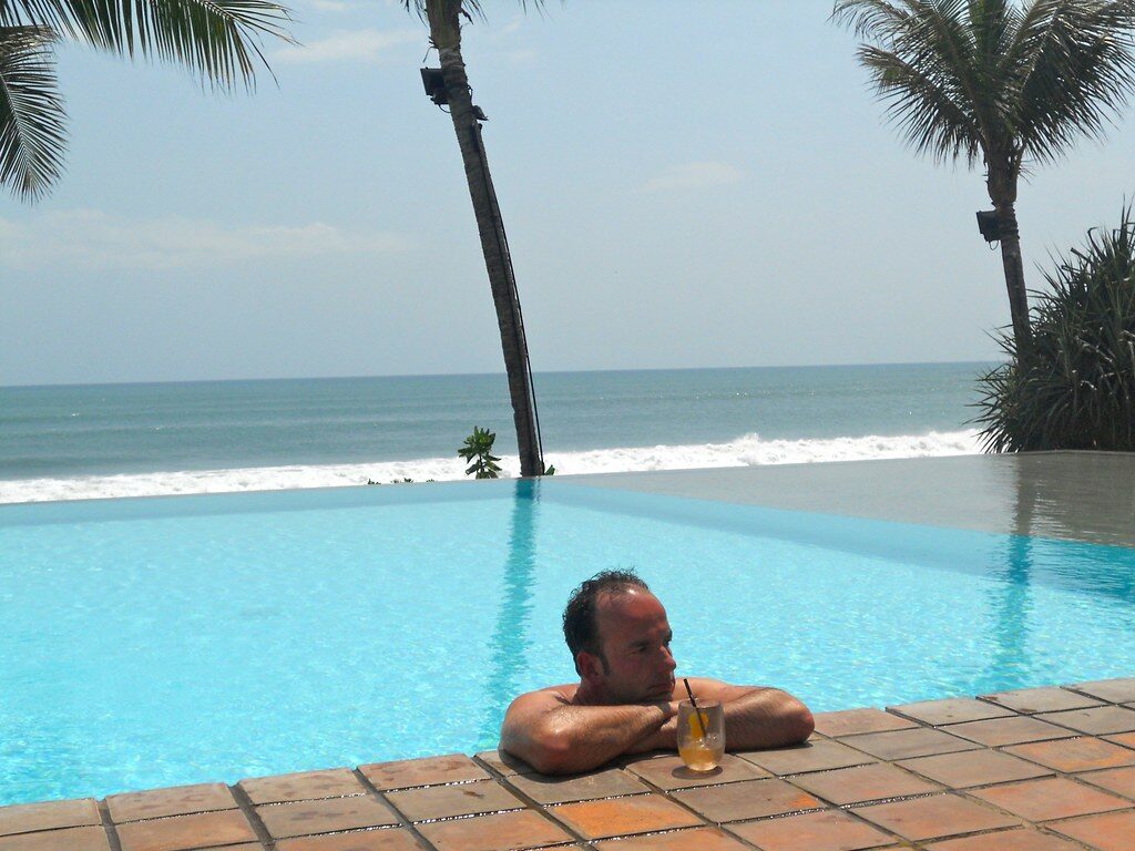 A guest in a villa infinity pool above the sea — the stylish-villa side of Seminyak.